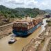 Large container ship moving through the Panama Canal during low-water conditions.